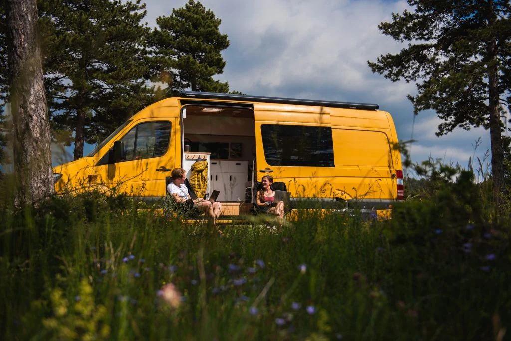 Charlie and Dale of Climbingvan working outside their campervan in France