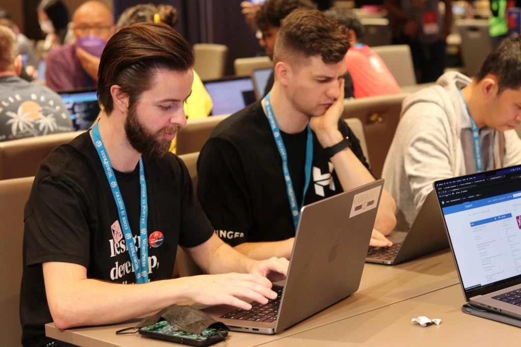 Colaboradores de WordPress trabajando en su proyecto de equipo durante el Día del Colaborador de WordCamp Asia 2023