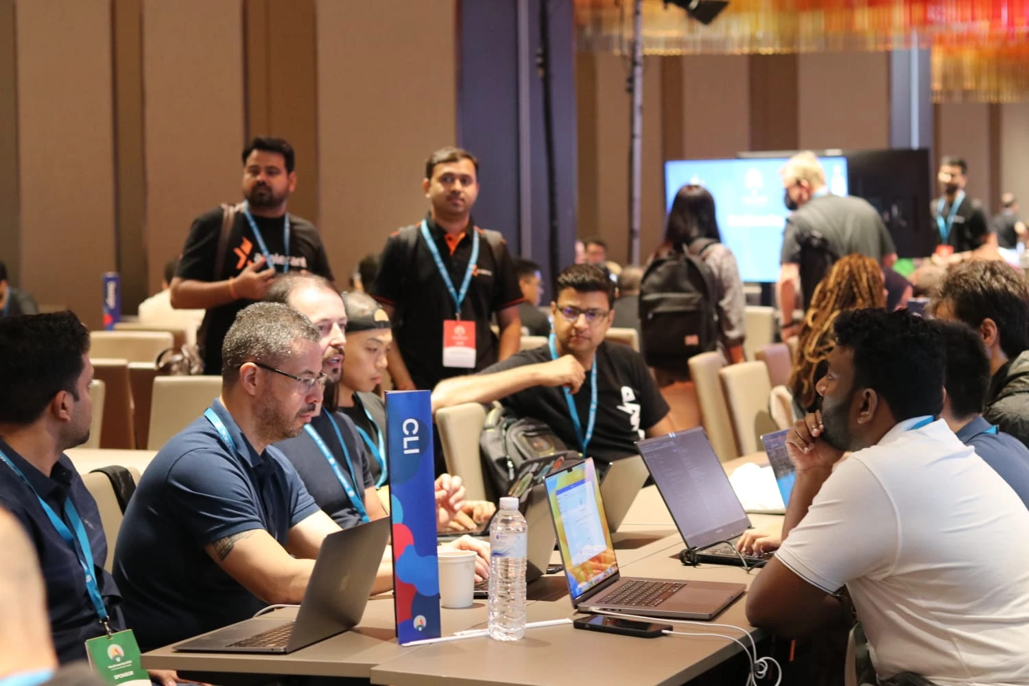 Colaboradores de WordPress trabajando y discutiendo en la mesa WP-CLI durante el Día del Colaborador de WordCamp Asia 2023