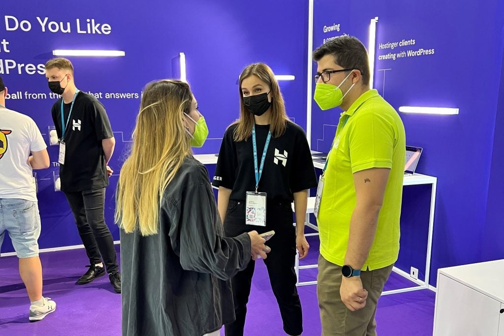 a Hostinger team member having a conversation with customers at the booth during WordCamp Europe 2022