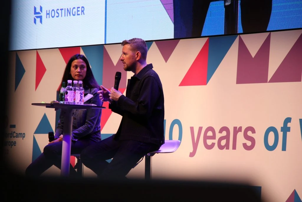 WordPress's co-founder, Matt Mullenweg, delivering a talk on stage in WordCamp Europe 2022 together with WordPress's Executive Director, Josepha Haden Chomphosy