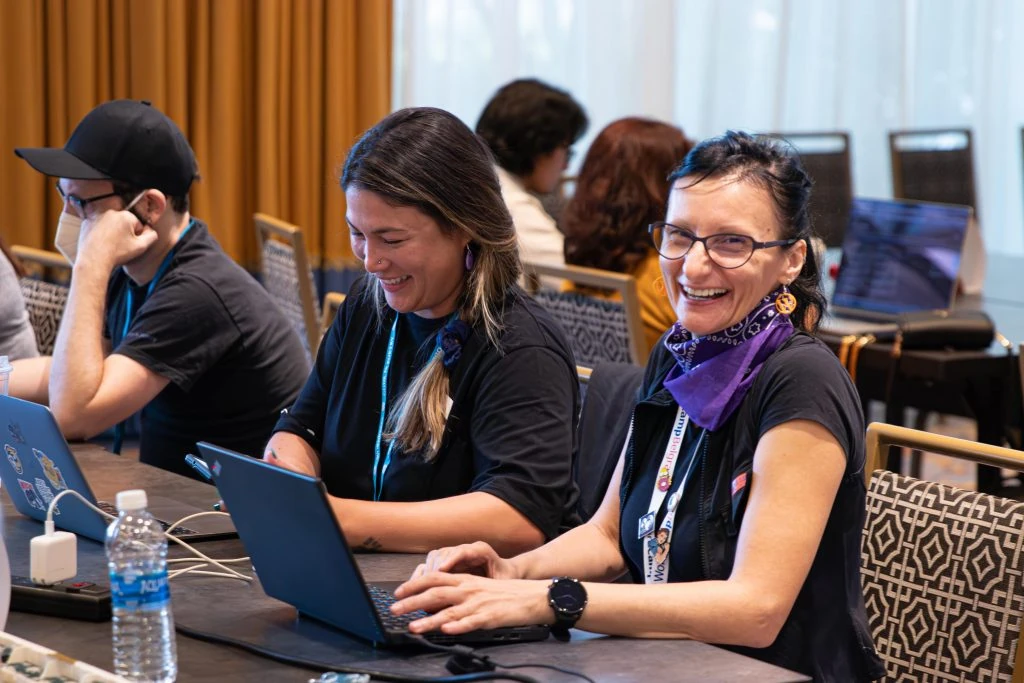 Emma Young, jefa de contenido de Hostinger, y Milana Cap, representante del equipo de documentación, en la mesa del equipo de documentación en WordCamp US 2023