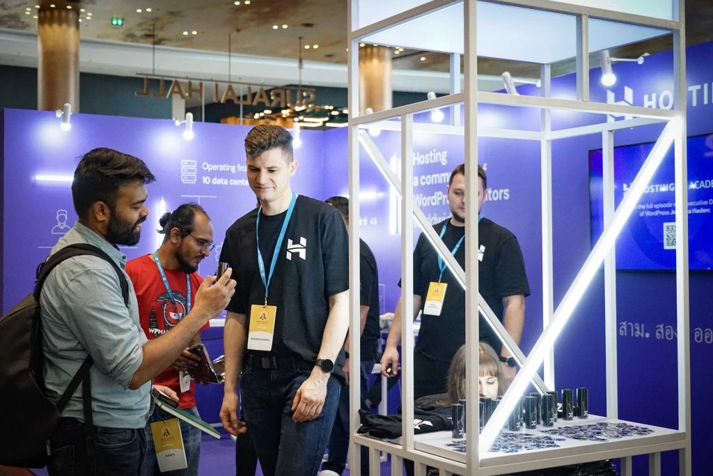 A Hostinger team member shows our merchandise to a booth visitor