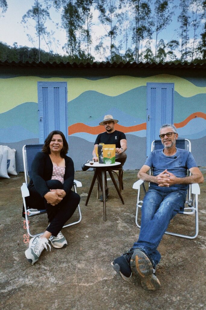 Talles sits with his parents in front of the farmhouse painted with a mountain landscape