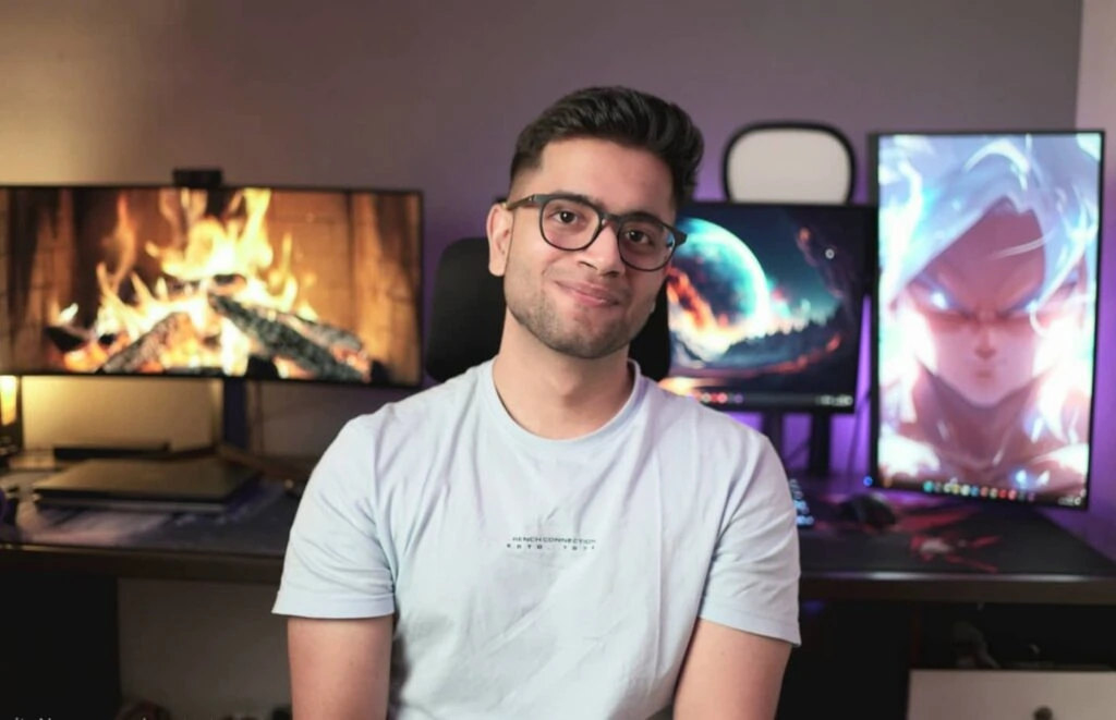 Ansh Bhawnani, founder of Bitten Tech, at his desk in front of monitors displaying a fireplace and anime artwork
