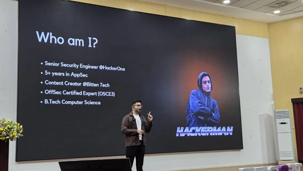 Ansh Bhawnani of Bitten Tech presenting on stage beside a "Who am I?" slide listing his security career and credentials