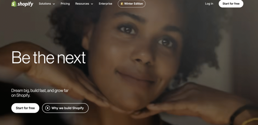 A close-up view of hands resting on a table, with a blurred background featuring text promoting Shopify services.