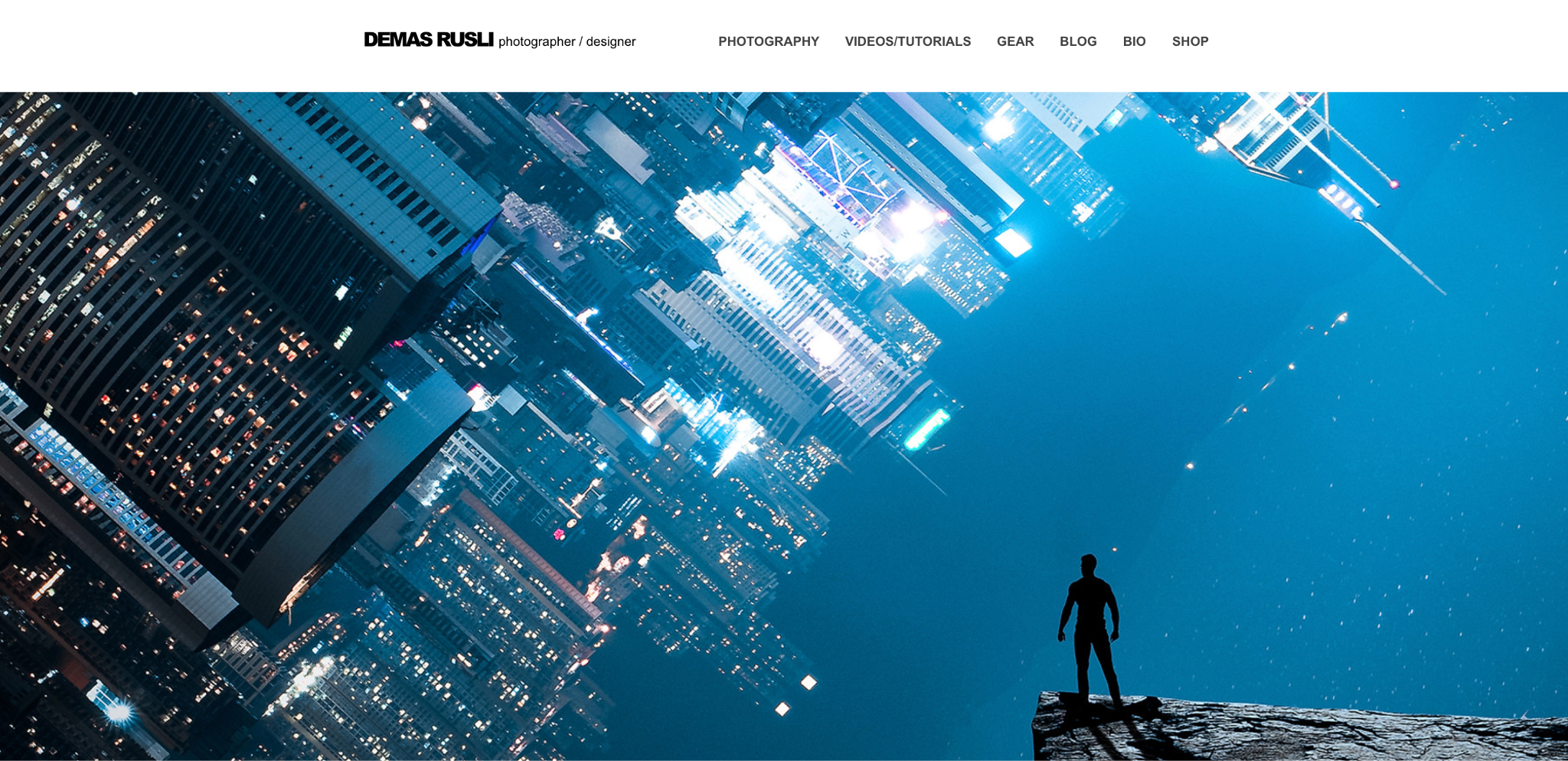 Demas Rusli's photography portfolio homepage with a dramatic full-width composite photo of a silhouetted figure at the edge of a cliff overlooking a blue-toned inverted cityscape